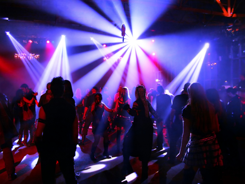 A dark club with people dancing on the dancefloor under the lights