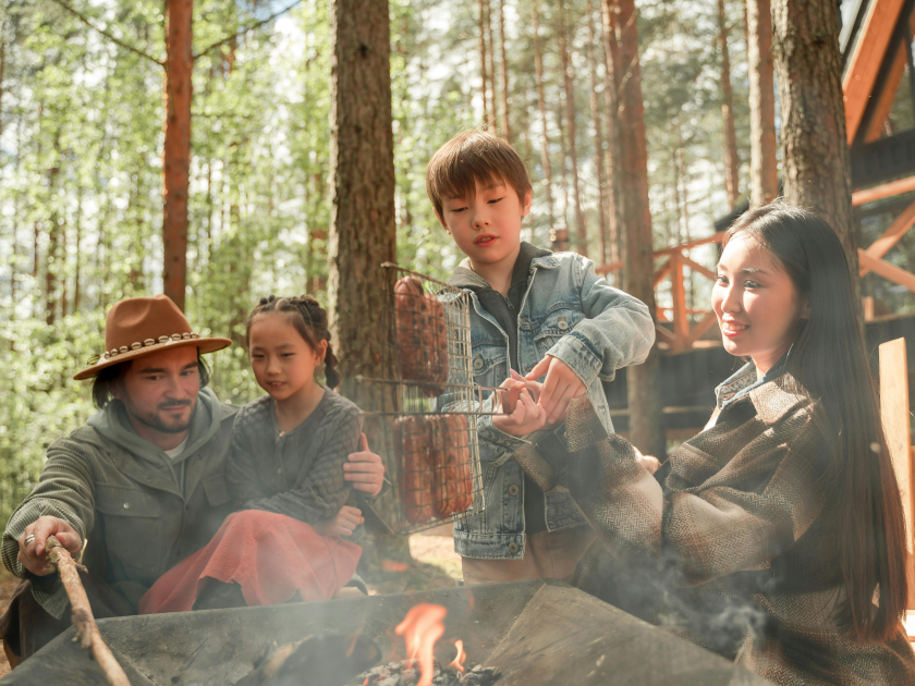 A family cooking hot dogs over a campfire while camping
