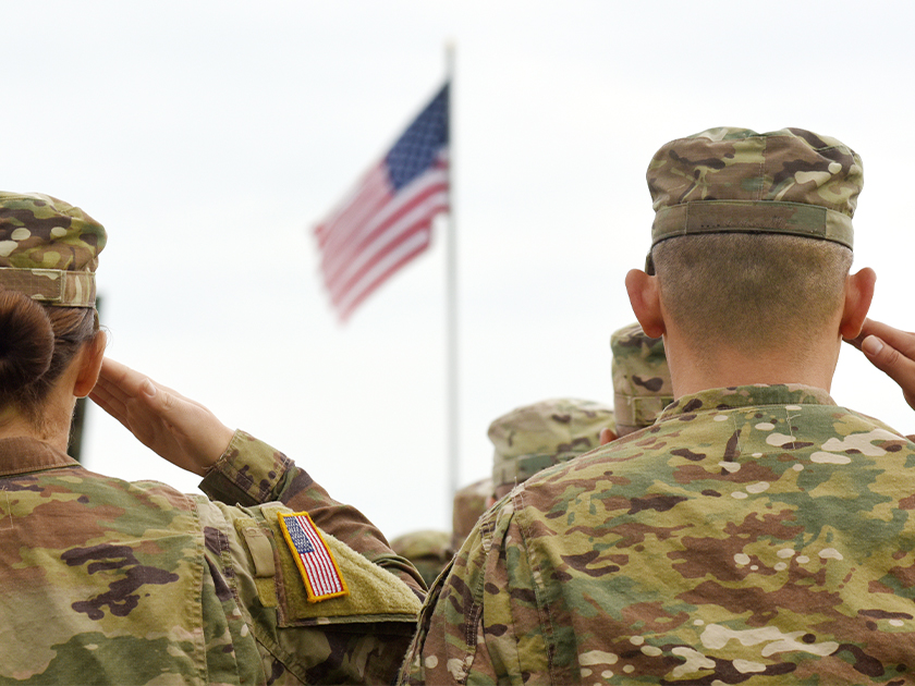 Ranks of US Armed Forces in Army Fatigues saluting the American Flag