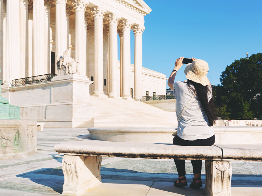 A tourist taking a photo of the United States Supreme Court with her cell phone
